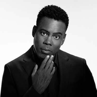 Black-and-white portrait of Chris Rock in a black suit